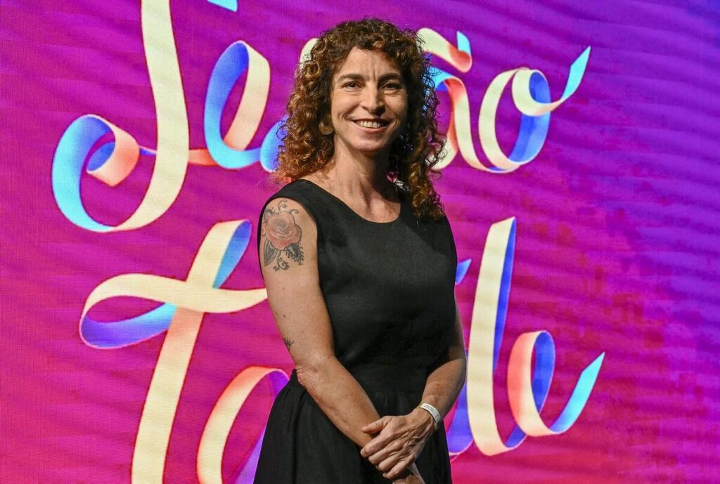 Rosane Svartman à frente do logo da Sessão da Tarde em evento comemorativo