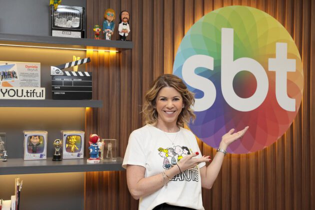 Daniela Beyruti à frente do logo do SBT em sua sala