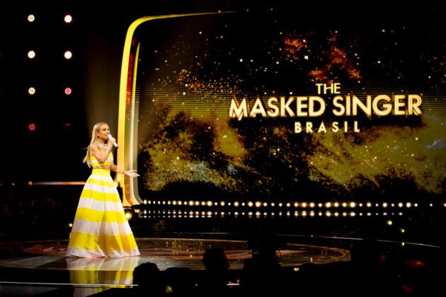 Eliana de vestido amarelo à frente do telão do The Masked Singer Brasil