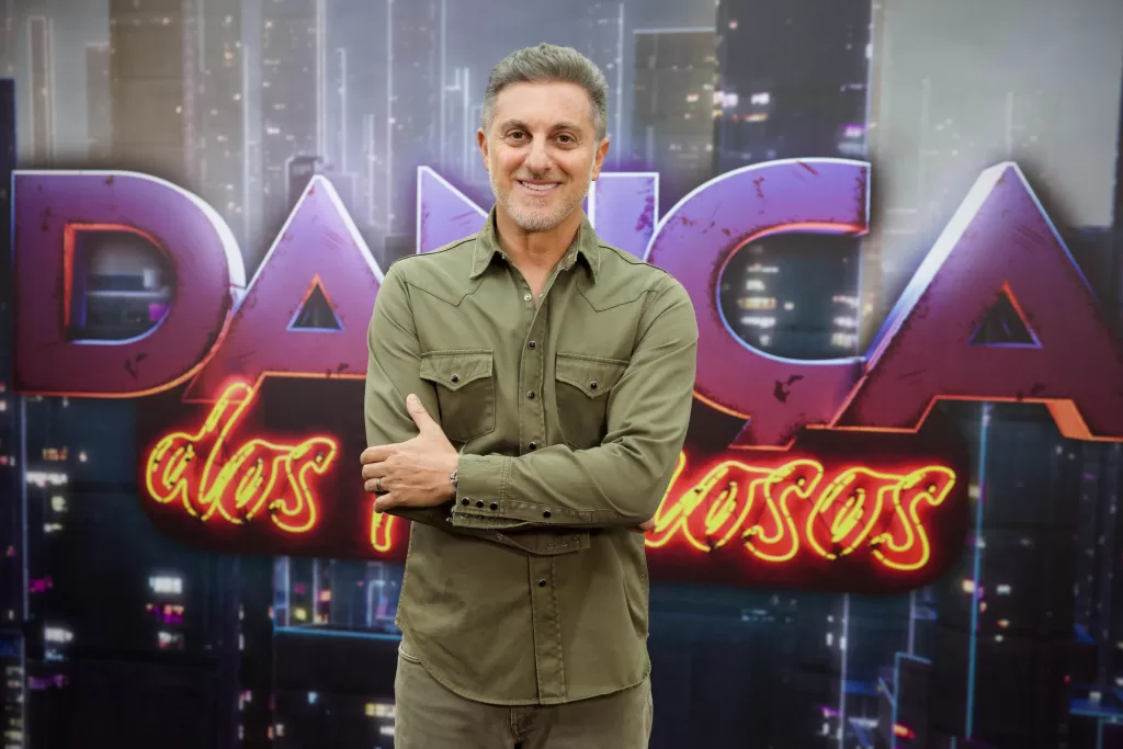 Luciano Huck à frente do logo da Dança dos Famosos