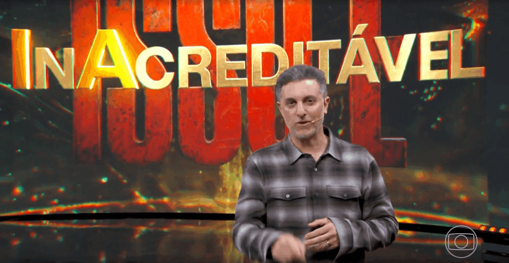 Luciano Huck à frente do logo do Isso é Inacreditável