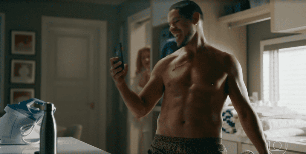 Iuri vê o celular na cozinha sem camisa